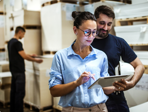 Two coworkers look at tablet in warehouse