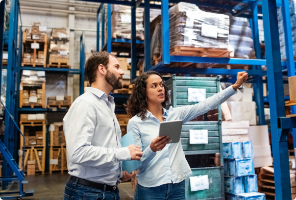 Two warehouse workers check inventory on tablet